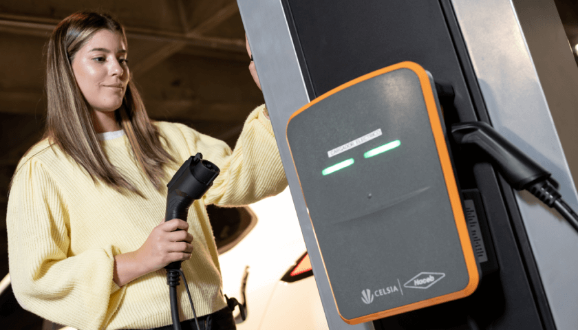 Foto de mujer frente a aparato para recargar autos eléctricos